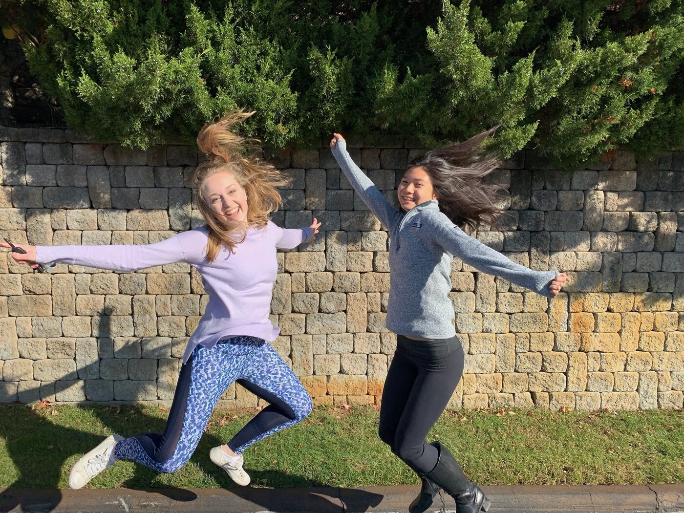 Karis and a friend jumping joyfully in an open field